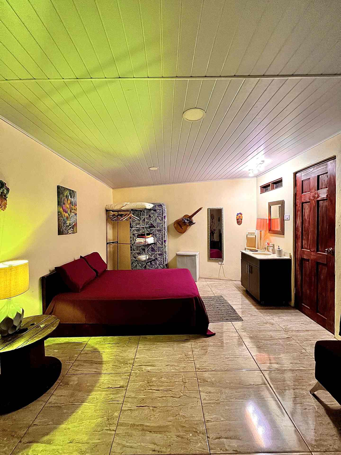 Garden studio bedroom with warm lighting, tiled floor, and simple furnishings